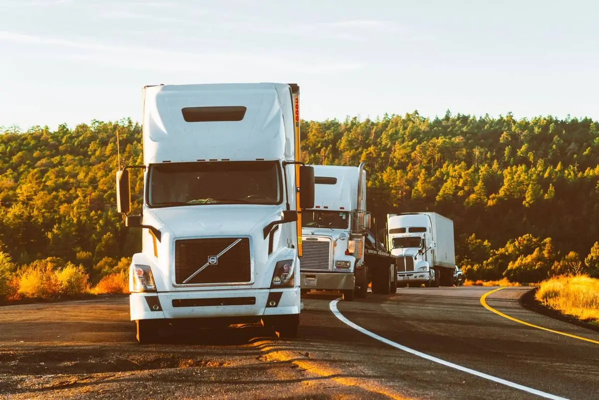 A line of semi trucks on a mountain road at golden hour